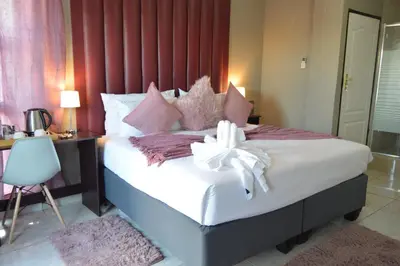 a bedroom with a bed with a white bow on it at Clifford's Rufaro Hotel, Conference & Spa in Burgersfort