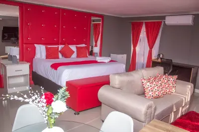 a bedroom with two beds and a red headboard at Clifford's Rufaro Hotel, Conference & Spa in Burgersfort