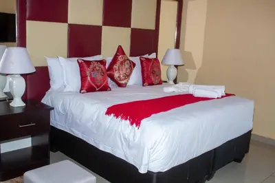 a bedroom with a large bed with red pillows at Clifford's Rufaro Hotel, Conference & Spa in Burgersfort