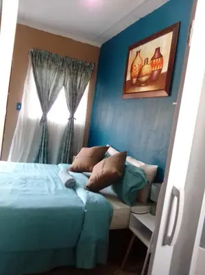 a blue bedroom with a bed and a window at Cosy Beds Web in Witbank