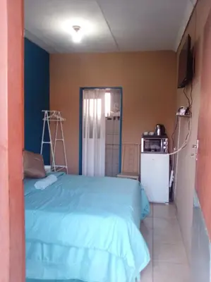 a bedroom with a blue bed and a refrigerator at Cosy Beds Web in Witbank