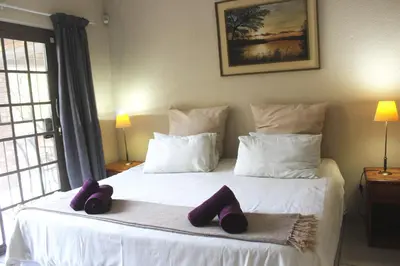a bedroom with a bed with purple slippers on it at Nature House in Marloth Park