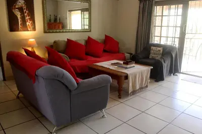 a living room with a red couch and a table at Nature House in Marloth Park