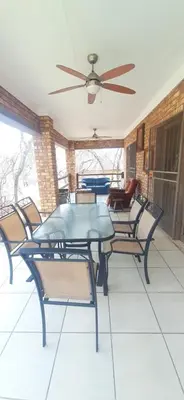a dining room table with chairs and a ceiling fan at Nature House in Marloth Park