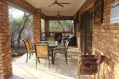 a patio with chairs and a table and a ceiling fan at Nature House in Marloth Park