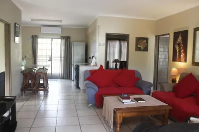 a living room with red couches and a table at Nature House in Marloth Park
