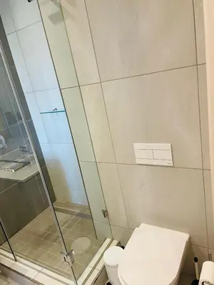 a bathroom with a toilet and a glass shower at Menlyn Maine Trilogy Hotel in Pretoria