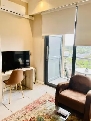a living room with a couch and a tv at Menlyn Maine Trilogy Hotel in Pretoria