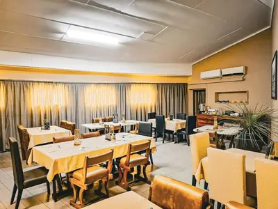 a restaurant with tables and chairs in a room at Musina Hotel in Musina
