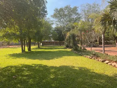 a park with green grass and trees and a building at Musina Hotel in Musina