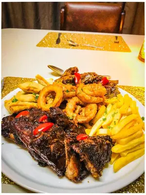 a plate of food with shrimp and fries on a table at Musina Hotel in Musina
