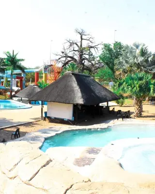 a resort with a thatch roof and a swimming pool at Sandriver Resort in Musina