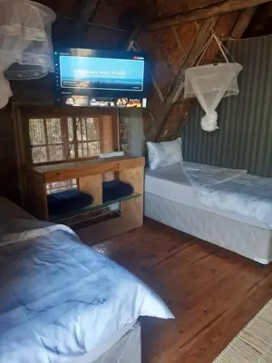 a room with two beds and a tv on the wall at African Bush Escape in Marloth Park