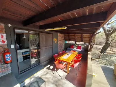 a patio with a table and chairs and a kitchen at African Bush Escape in Marloth Park