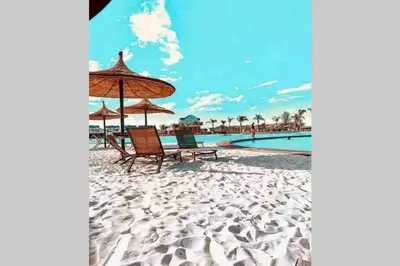 a beach with chairs and an umbrella and a pool at The Blyde Silverlakes in Boschkop