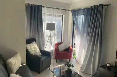 a living room with a red chair and a window at The Blyde Silverlakes in Boschkop
