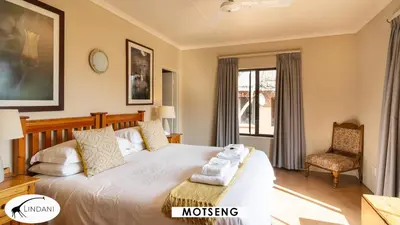 a bedroom with a large bed and a chair at Lindani Game and Lodges in Vaalwater