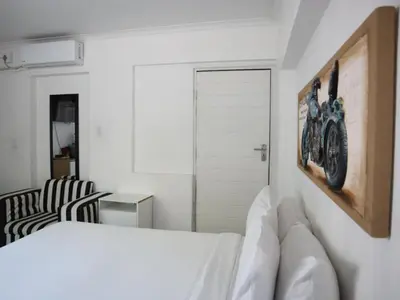a white bedroom with a bed and a chair at Casa Palmeira in Nelspruit