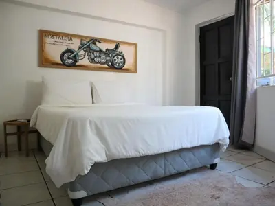 a bedroom with a white bed with a motorcycle on the wall at Casa Palmeira in Nelspruit