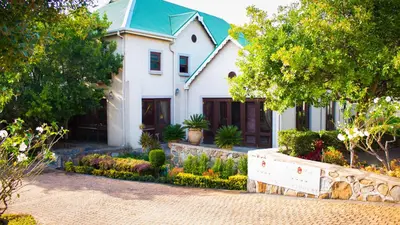 a white house with a green roof at Candlewoods Guesthouse in Centurion