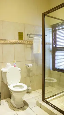 a bathroom with a toilet and a shower at Candlewoods Guesthouse in Centurion