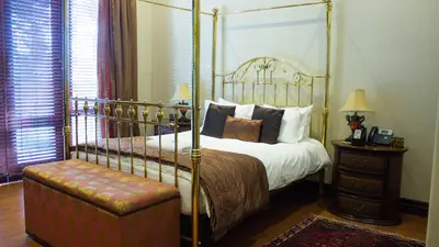 a bedroom with a four poster bed and a stool at Candlewoods Guesthouse in Centurion
