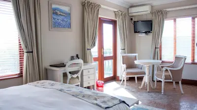 a bedroom with a bed and a table and chairs at Candlewoods Guesthouse in Centurion