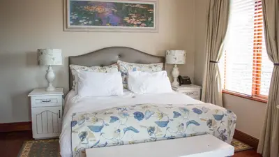 a bedroom with a bed with a blue and white comforter at Candlewoods Guesthouse in Centurion