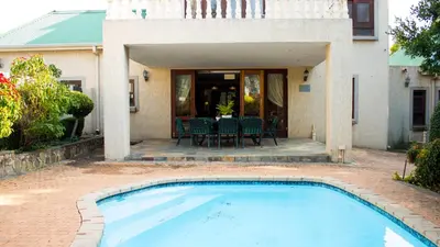 a swimming pool in front of a house at Candlewoods Guesthouse in Centurion