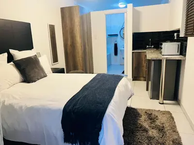 a bedroom with a large bed and a kitchen at Zindiza Guesthouse in Witbank