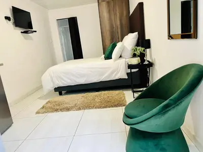 a bedroom with a green chair and a bed at Zindiza Guesthouse in Witbank