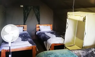 a room with two beds and a fan in a tent at Chosen Glamping Tents in Graskop