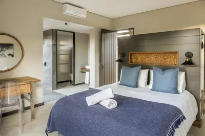 a bedroom with a large bed with blue pillows at Rixile Kruger Lodge in Skukuza