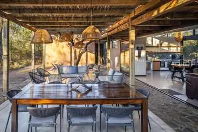 a dining room with a large wooden table and chairs at Rixile Kruger Lodge in Skukuza