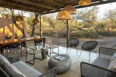 a patio with chairs and a wooden table and a table and chairs at Rixile Kruger Lodge in Skukuza