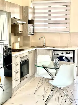 a kitchen with a glass table and white chairs at Ground Floor Apartment Midrand in Midrand