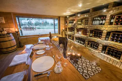 a dining room with a table with wine bottles at Kambaku River Sands in Timbavati Game Reserve