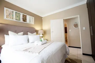 a bedroom with a large bed with white pillows at URlyfstyle 5 bedrooms 10km from OR Tambo Int Airport in Kempton Park
