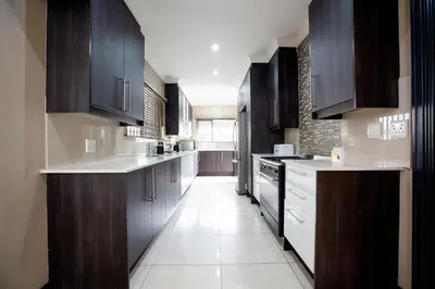 a kitchen with dark wood cabinets and white appliances at URlyfstyle 5 bedrooms 10km from OR Tambo Int Airport in Kempton Park