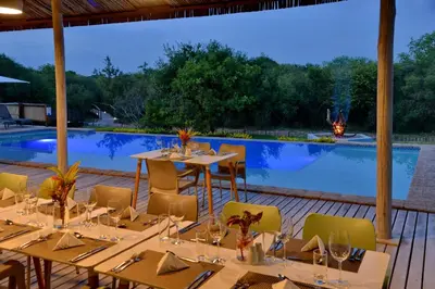 a dining area with tables and chairs and a pool at Kruger Safari Lodge in Manyeleti Game Reserve