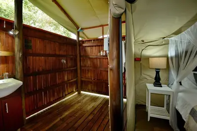 a room with a bed and a sink in a tent at Kruger Safari Lodge in Manyeleti Game Reserve