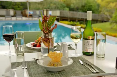 a table with glasses of wine and a plate of food at Kruger Safari Lodge in Manyeleti Game Reserve