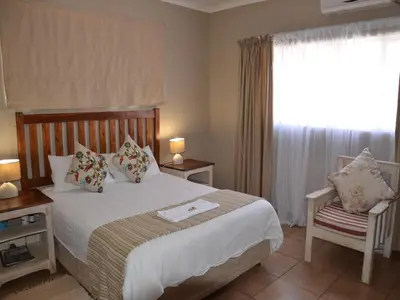 a bedroom with a bed and a window and a chair at Stoep Cafe Guest House in Komatipoort