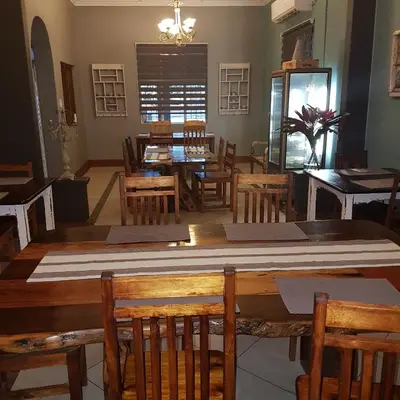 a dining room with a large wooden table and chairs at Stoep Cafe Guest House in Komatipoort