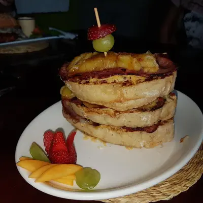 a stack of pancakes on a plate with strawberries at Stoep Cafe Guest House in Komatipoort