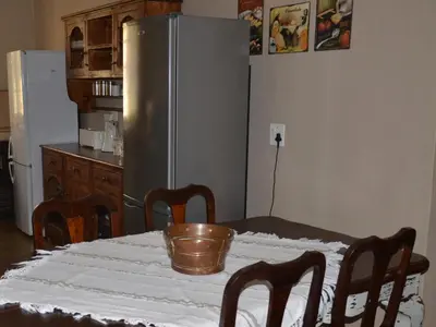 a kitchen with a table with a silver refrigerator at Stoep Cafe Guest House in Komatipoort