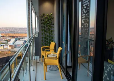 two yellow chairs on a balcony with a view at Modern 1 Bedroom Executive Apartment in Waterfall in Midrand