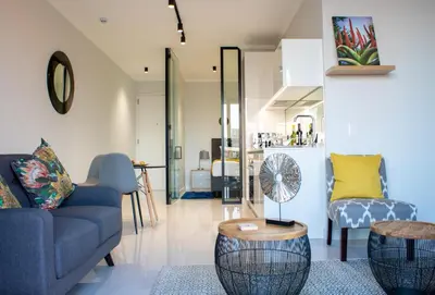 a living room with a blue couch and two chairs at Modern 1 Bedroom Executive Apartment in Waterfall in Midrand