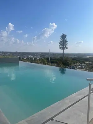 a large blue swimming pool with a tree in the background at Modern 1 Bedroom Executive Apartment in Waterfall in Midrand