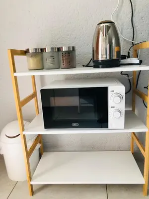 a microwave on a white shelf with a toaster oven at Zinathi Lodge in Lebowakgomo